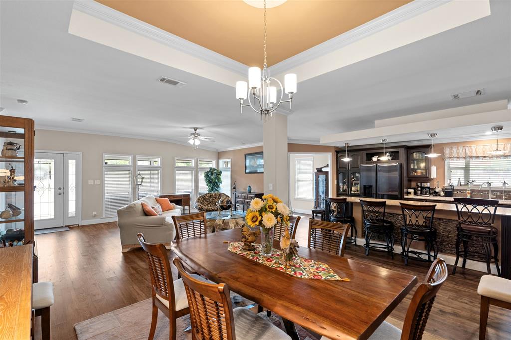 An open-concept dining and living area features wood flooring, a tray ceiling, and kitchen seating — 2715 9TH AVENUE N, ST PETERSBURG, FL