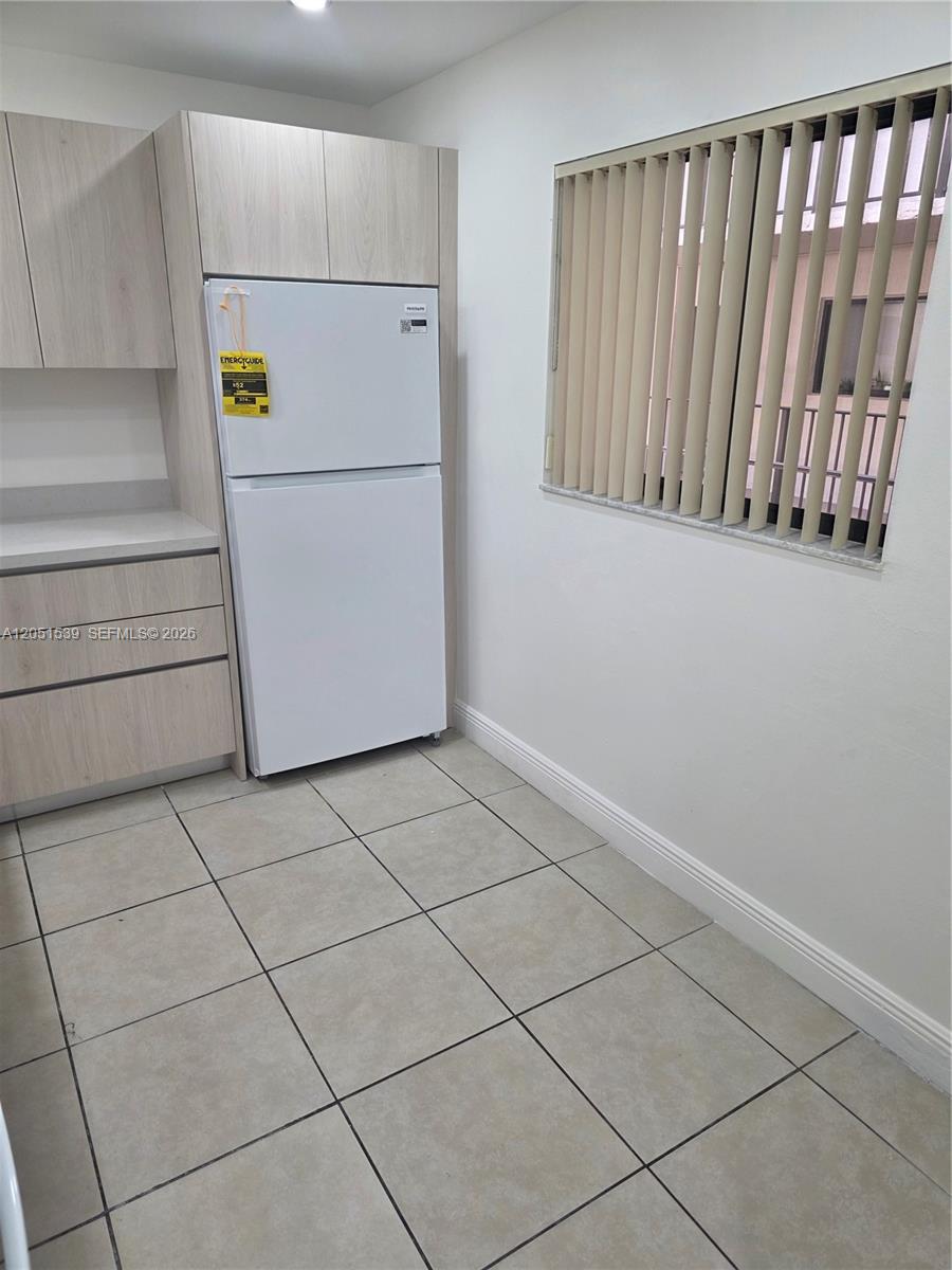 A kitchen features light wood cabinets, a white refrigerator, and beige tile flooring — 8025 SW 107th Ave # 202, Miami FL 33173, MIAMI, FL