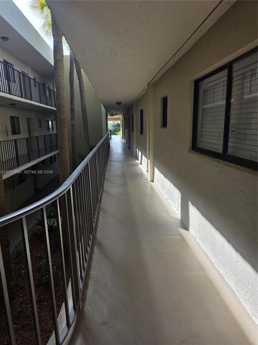 An outdoor walkway with a metal railing overlooks a courtyard with palm trees — 8025 SW 107th Ave # 202, Miami FL 33173, MIAMI, FL