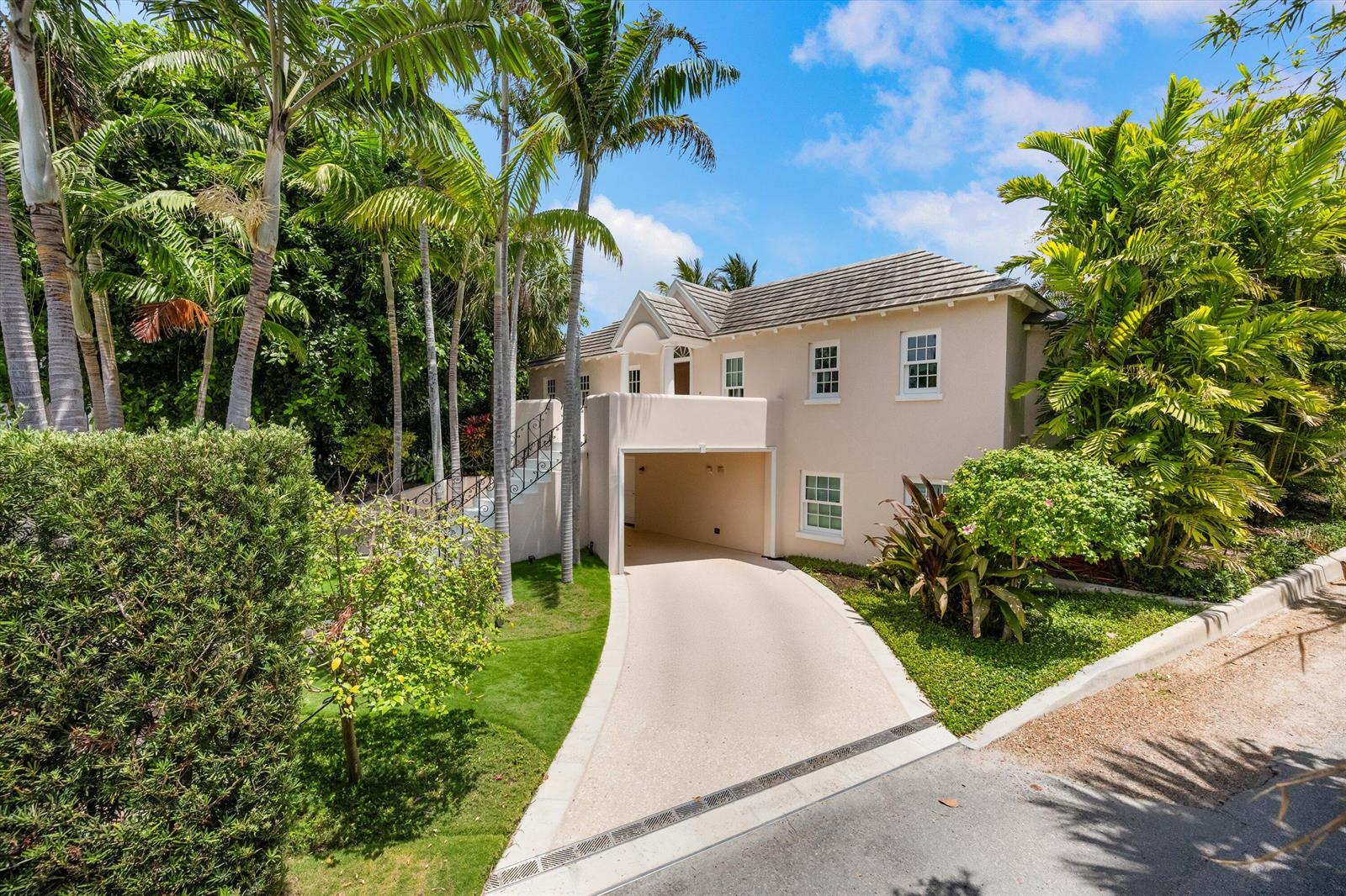 A two-story beige house with a built-in garage, surrounded by palm trees and lush landscaping — 750 S County Road, Palm Beach FL 33480, PALM BEACH, FL