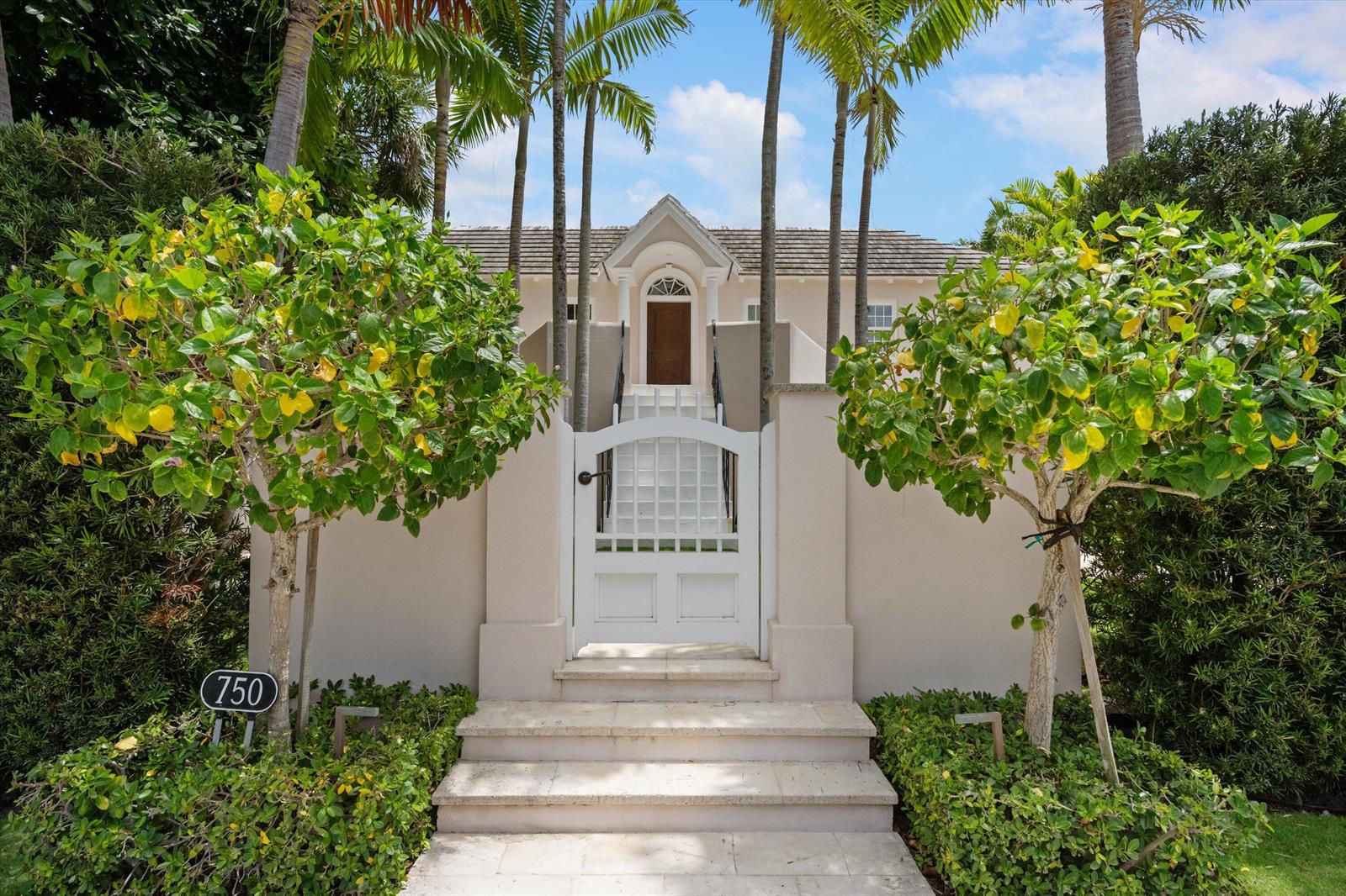 A white gate and stone steps lead to the elevated entrance of a tan house — 750 S County Road, Palm Beach FL 33480, PALM BEACH, FL