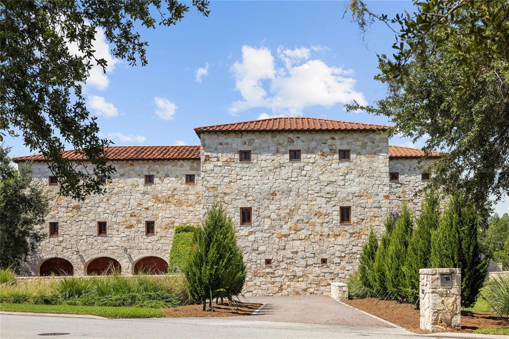 A large, three-story stone house with a red tile roof and arched ground-level openings — 1571 OCEANVIEW DRIVE, ST PETERSBURG, FL