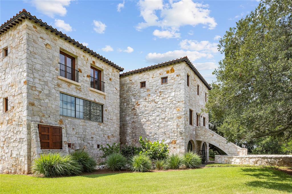 A multi-story stone house with a tiled roof, arched stone bridge, and landscaped lawn — 1571 OCEANVIEW DRIVE, ST PETERSBURG, FL
