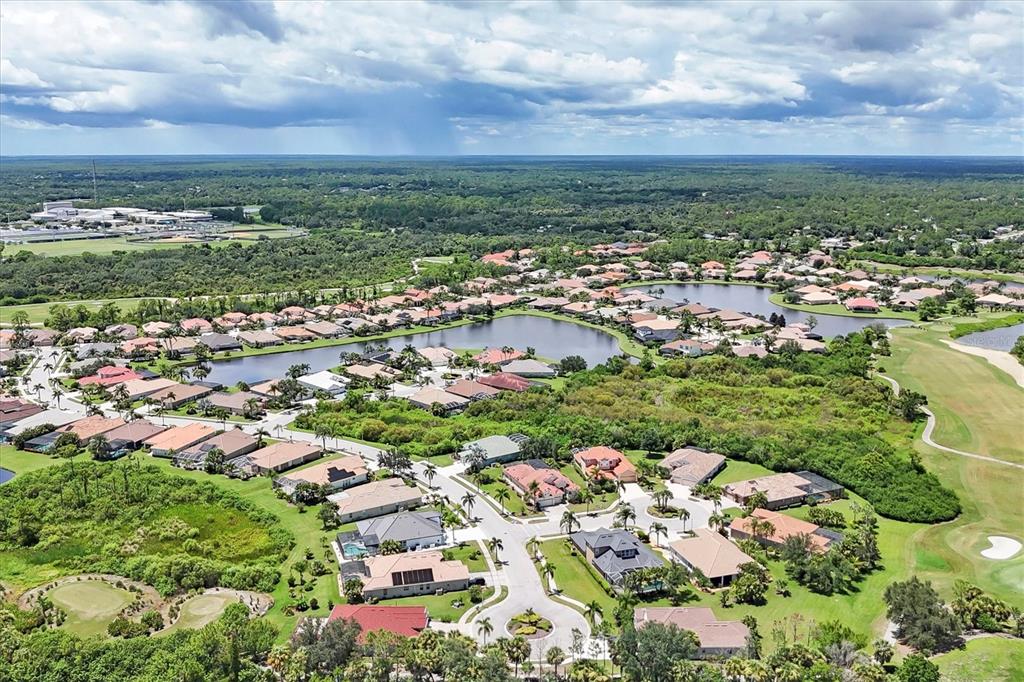 An aerial view shows a suburban residential neighborhood with houses surrounding a central lake — 5158 GRAND PALMETTO WAY, NORTH PORT, FL