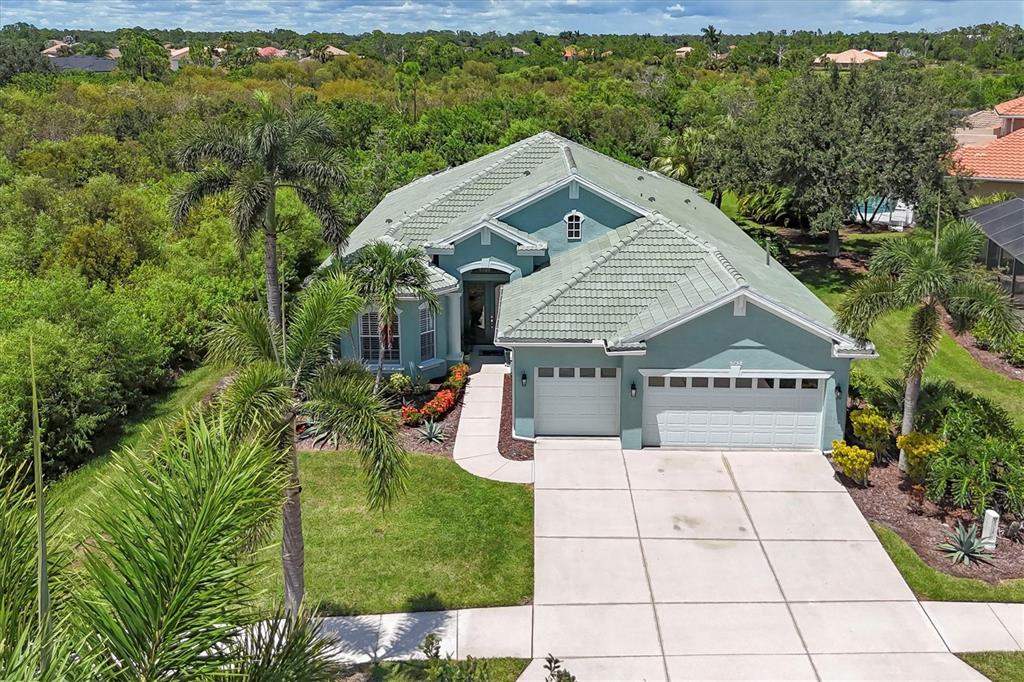 An aerial view shows a teal, single-story house with a tiled roof and a concrete driveway — 5158 GRAND PALMETTO WAY, NORTH PORT, FL