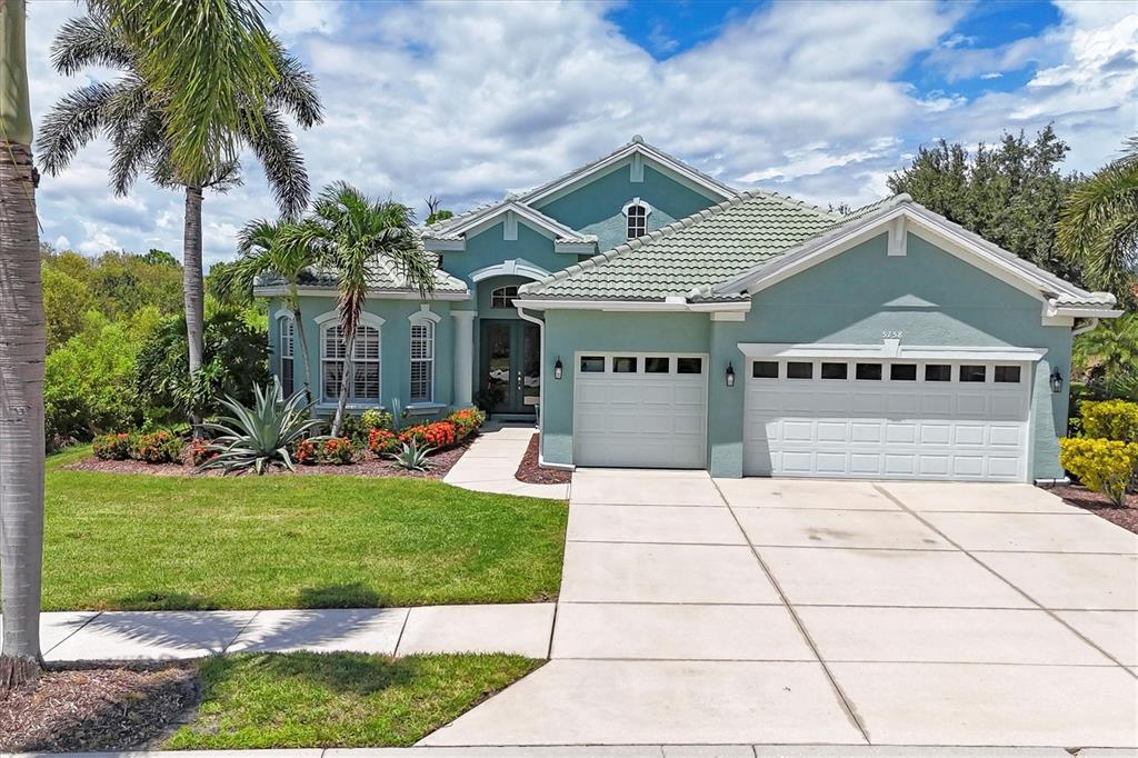A teal single-story house with a tile roof, a three-car garage, and palm trees — 5158 GRAND PALMETTO WAY, NORTH PORT, FL
