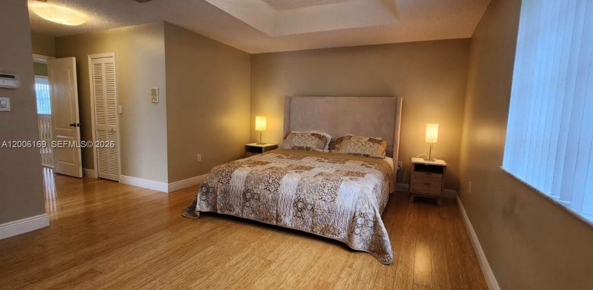 A bedroom features light wood flooring, a beige upholstered headboard, and two matching bedside lamps — 9309 SW 166th Ct, Miami FL 33196, MIAMI, FL