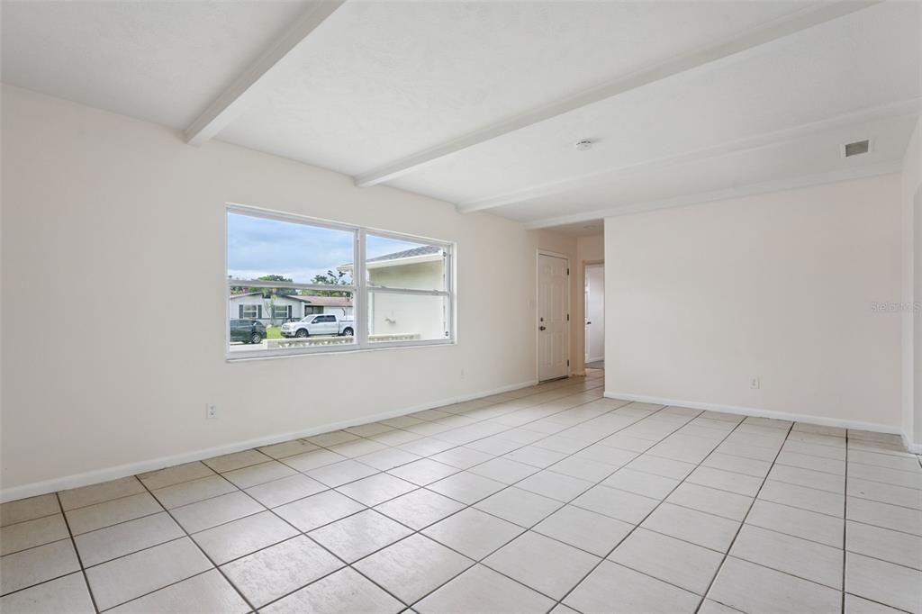 A bright, empty room features white walls, a tiled floor, and a large window — 1605 PURITAN AVENUE, WINTER PARK, FL