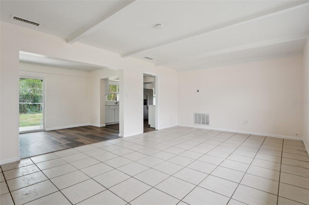 An interior view shows a tiled living area connected to a kitchen and sliding glass doors — 1605 PURITAN AVENUE, WINTER PARK, FL