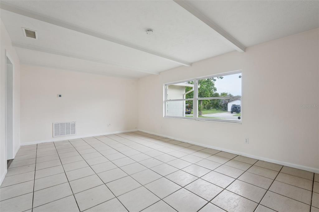 An empty room with light-colored tile flooring, white walls, and a large window — 1605 PURITAN AVENUE, WINTER PARK, FL