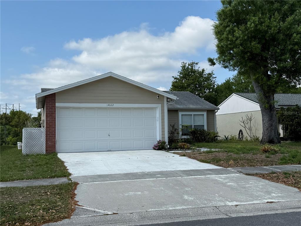 A single-story house with a beige exterior, a two-car garage, and a concrete driveway — 14022 CITRUS POINTE DRIVE, TAMPA, FL