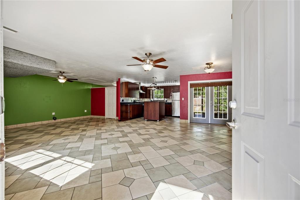 An open-concept room features tiled floors, a kitchen with dark cabinetry, and colorful accent walls — 6517 NW 27TH STREET, GAINESVILLE, FL