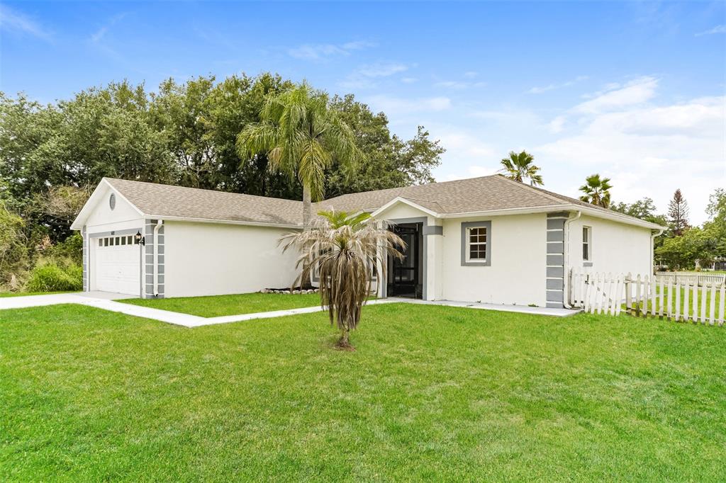 A single-story white house with a gray roof, a garage, and a front lawn — 602 COTULLA DRIVE, KISSIMMEE, FL