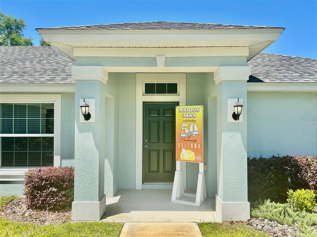 The exterior of a light green house features a covered entryway with a dark door — 13300 SW 43RD COURT, OCALA, FL
