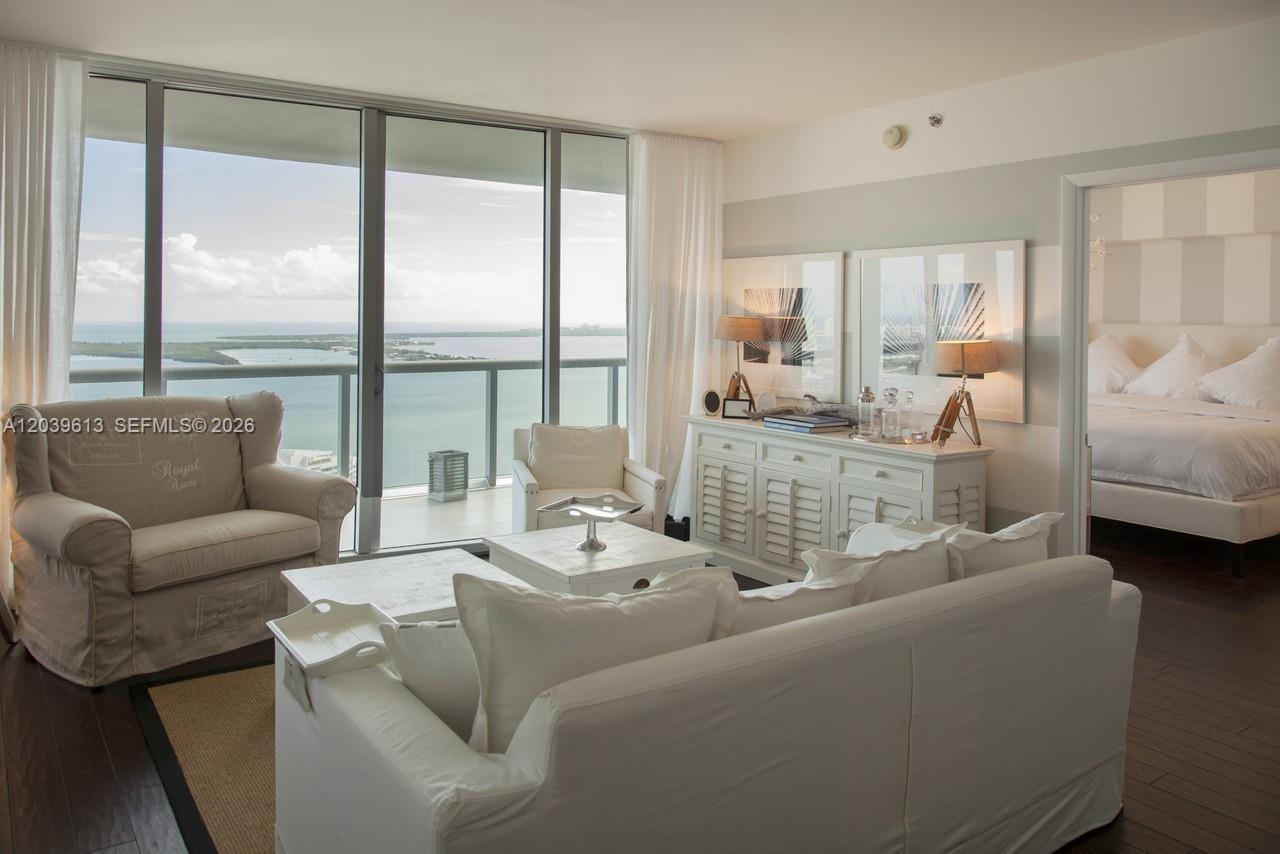 A living room with white furniture and a balcony overlooking the ocean and bay — 465 Brickell Ave # 4703, Miami FL 33131, MIAMI, FL