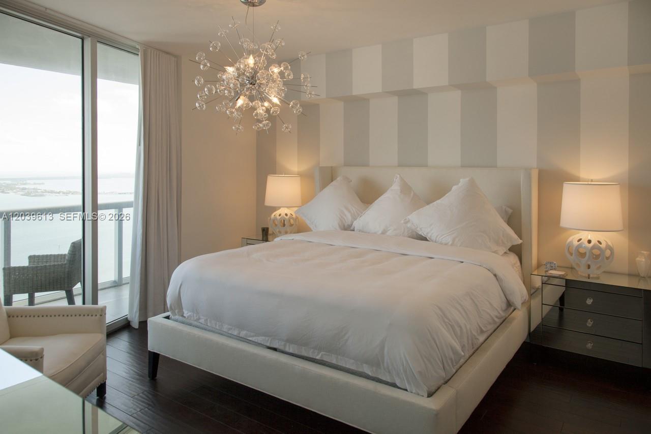 A bedroom features a bed with white linens, a sputnik chandelier, and striped wallpaper — 465 Brickell Ave # 4703, Miami FL 33131, MIAMI, FL