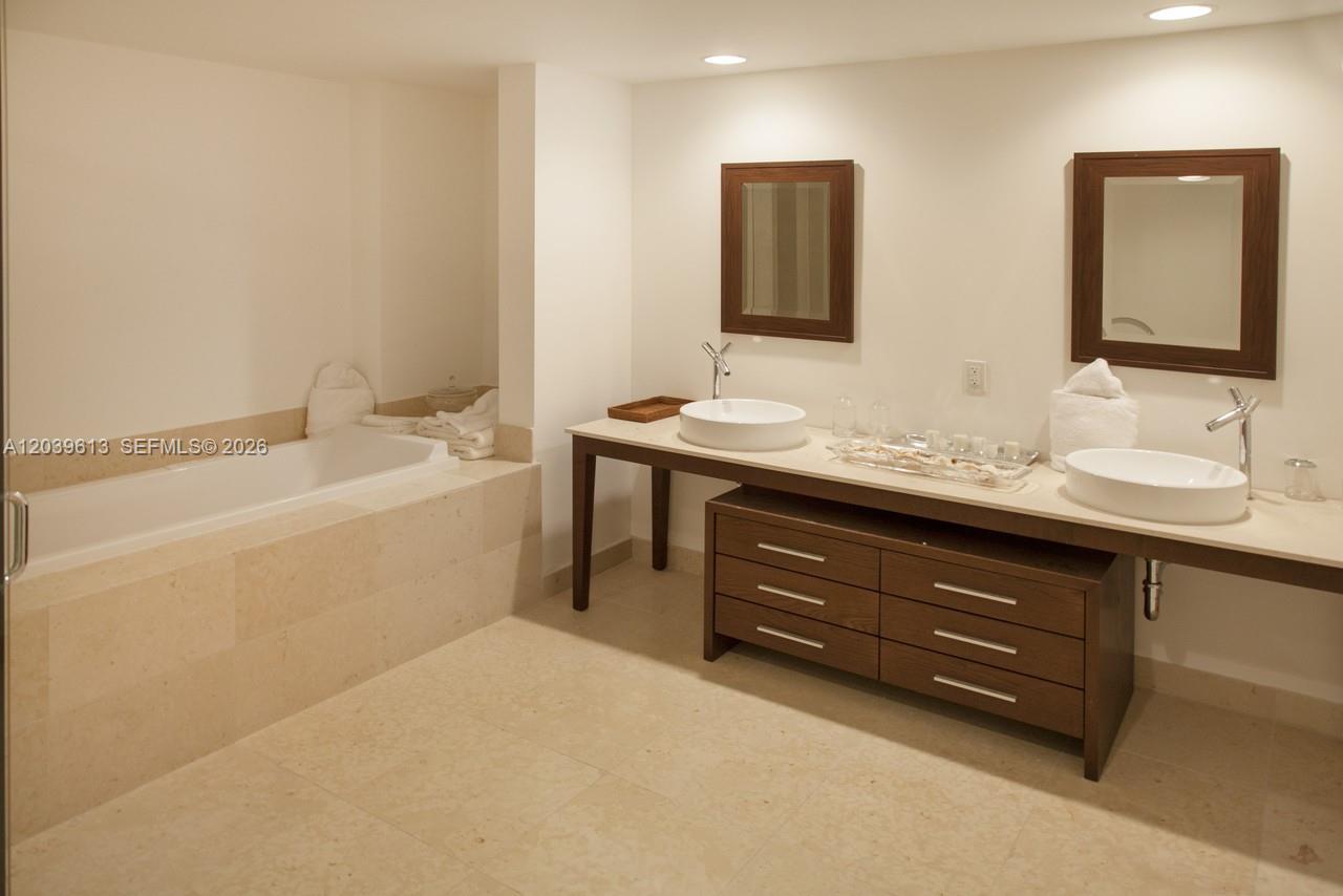 A bathroom features a soaking tub, a double vanity with vessel sinks, and tile flooring — 465 Brickell Ave # 4703, Miami FL 33131, MIAMI, FL