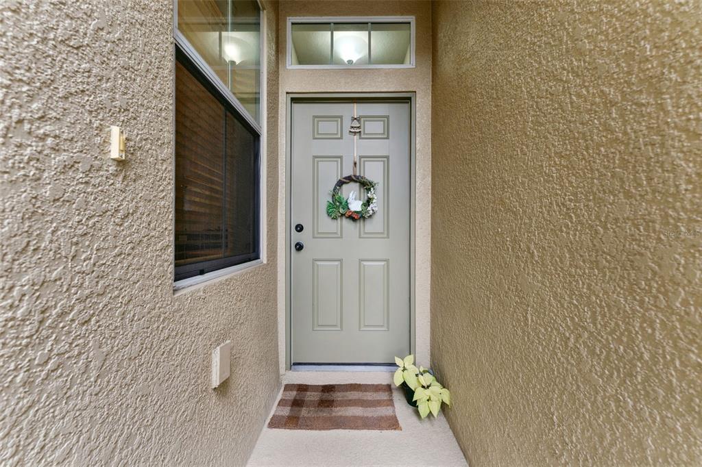 A light green front door with a wreath sits in a stucco-walled entryway — 2129 LENNOX DALE LANE, BRANDON, FL