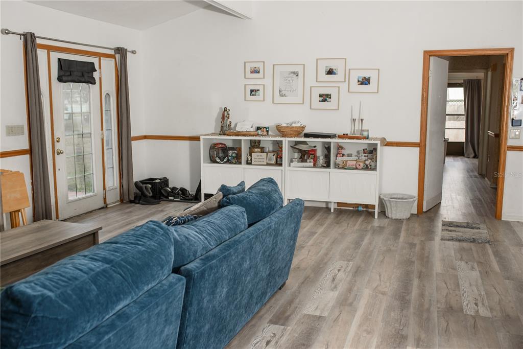 A living room features a blue sofa, white storage cabinets, and wood-look flooring — 5644 ANTOINETTE STREET, SARASOTA, FL