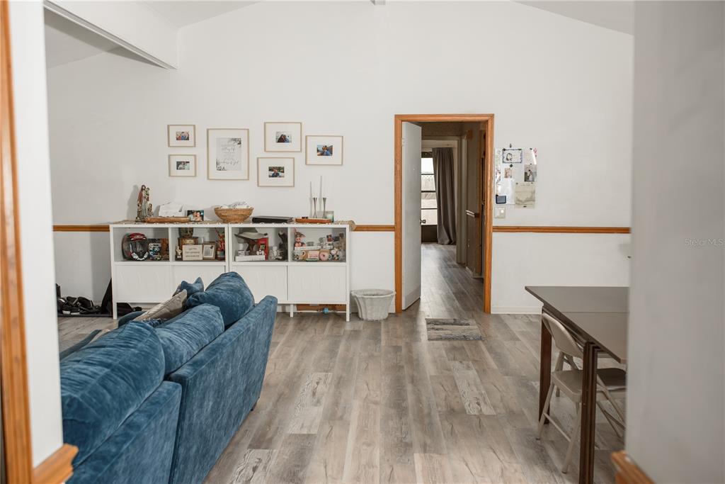 A living room features wood-look flooring, a blue sectional sofa, and a white storage unit — 5644 ANTOINETTE STREET, SARASOTA, FL