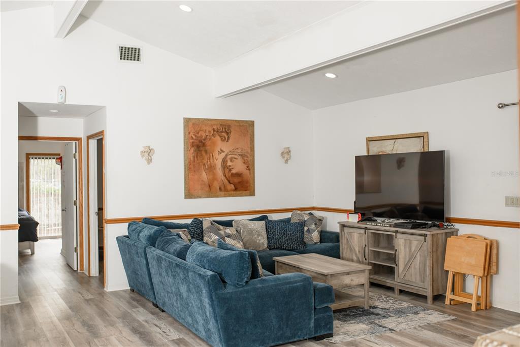 A living room features a blue sectional sofa, a wooden media console, and vaulted ceilings — 5644 ANTOINETTE STREET, SARASOTA, FL