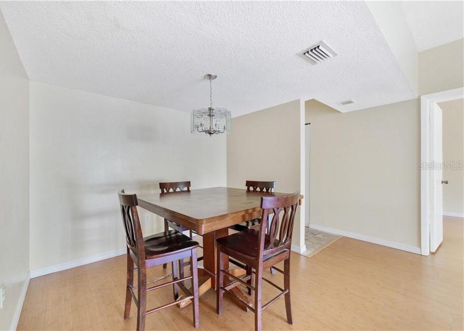 A dining area features a wooden table with four chairs under a glass chandelier — 3254 S SEMORAN BOULEVARD UNIT 21, ORLANDO, FL