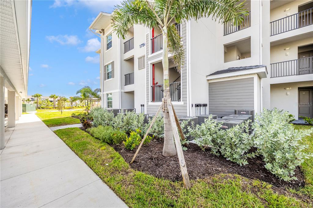 A multi-story apartment building exterior features a sidewalk, landscaping, and a palm tree — 17565 OPAL SAND DRIVE UNIT 202, VENICE, FL