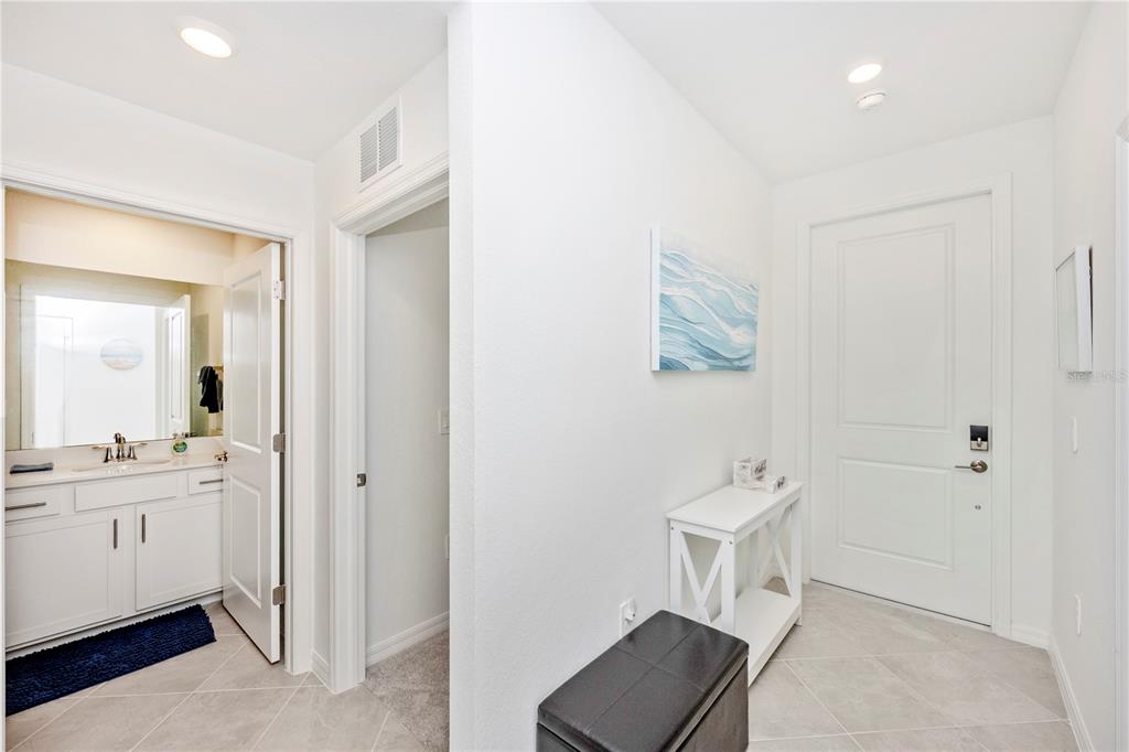 A bright entryway features a white console table, a black storage bench, and a bathroom door — 17565 OPAL SAND DRIVE UNIT 202, VENICE, FL