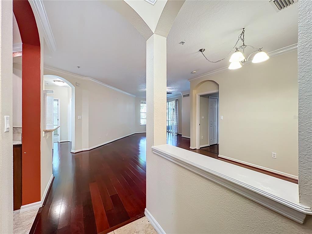 An interior view shows a hallway with dark hardwood floors, beige walls, and arched doorways — 11434 JASPER KAY TERRACE UNIT 106, WINDERMERE, FL