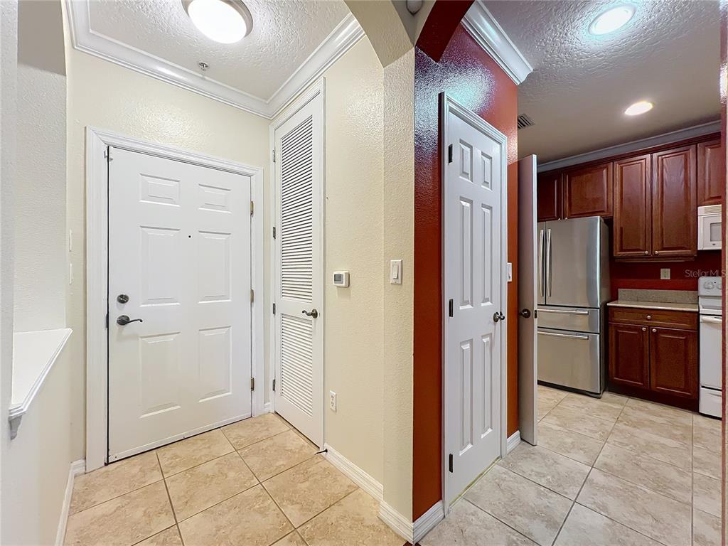 An entryway with tile flooring leads to a kitchen with dark wood cabinets and appliances — 11434 JASPER KAY TERRACE UNIT 106, WINDERMERE, FL