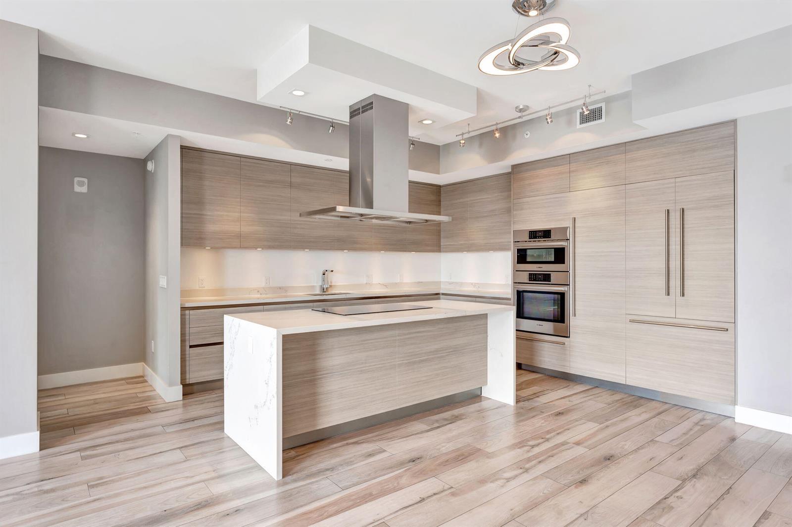 A modern kitchen features light wood cabinetry, a white marble island, and stainless steel appliances — 155 E Boca Raton Road # 719, Boca Raton FL 33432, BOCA RATON, FL