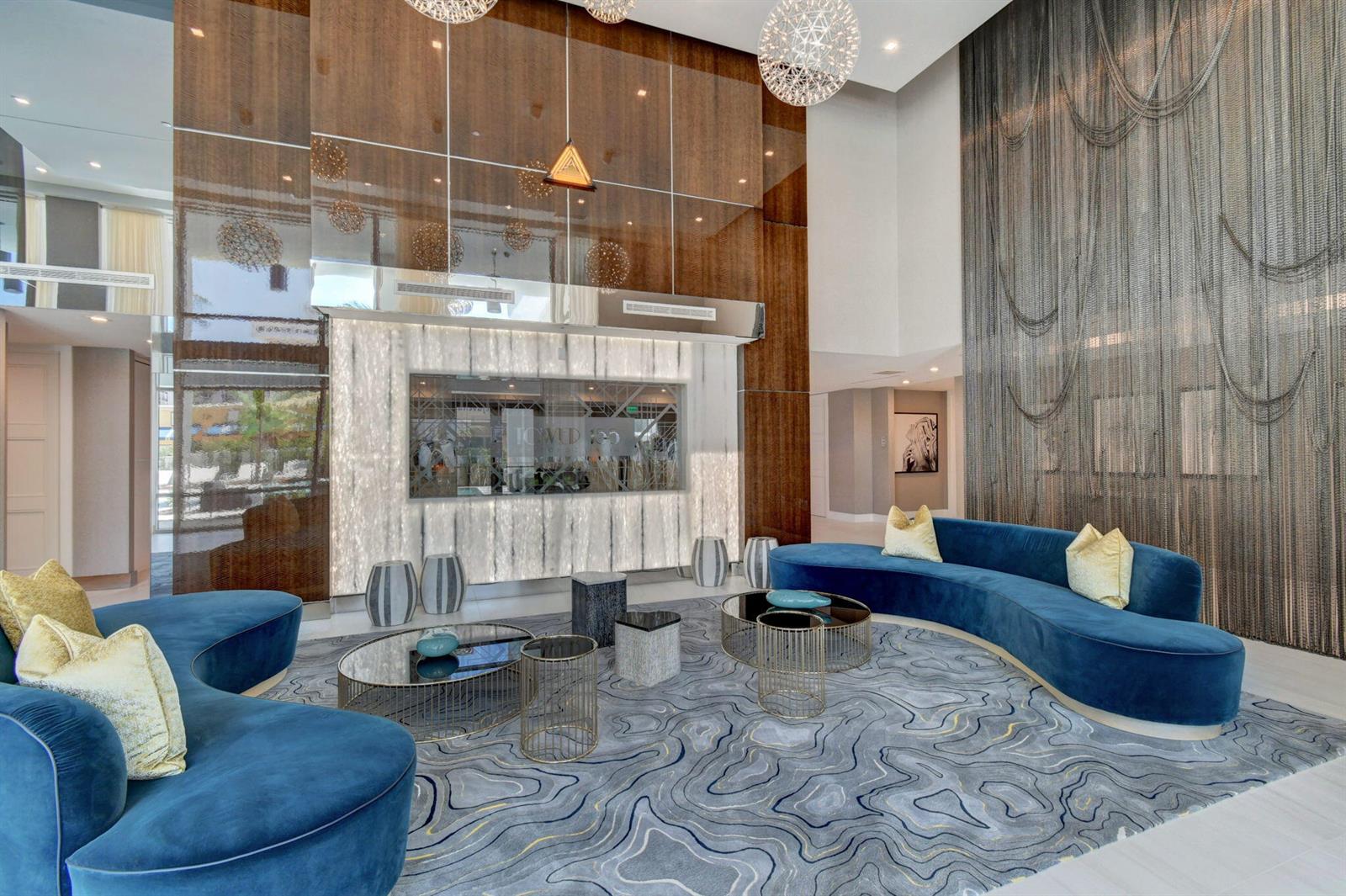 A modern lobby features two curved blue sofas, a patterned rug, and a backlit wall — 155 E Boca Raton Road # 719, Boca Raton FL 33432, BOCA RATON, FL