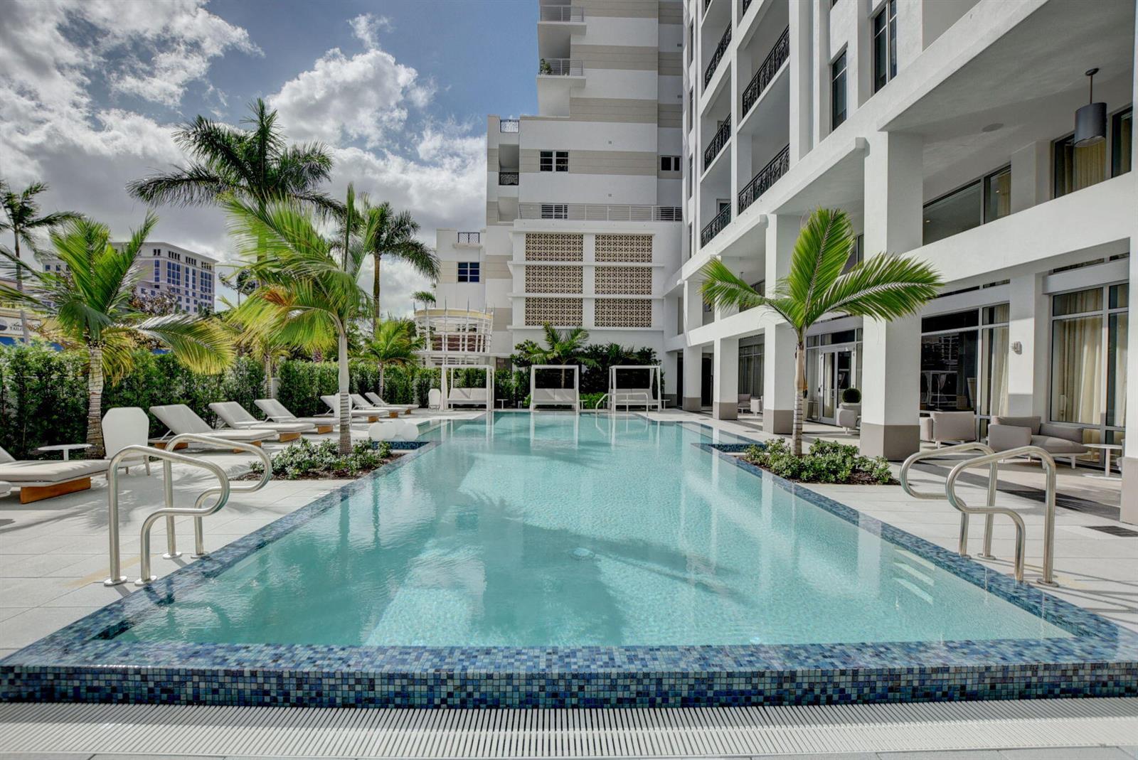 A rectangular swimming pool sits on a paved deck surrounded by palm trees and buildings — 155 E Boca Raton Road # 719, Boca Raton FL 33432, BOCA RATON, FL
