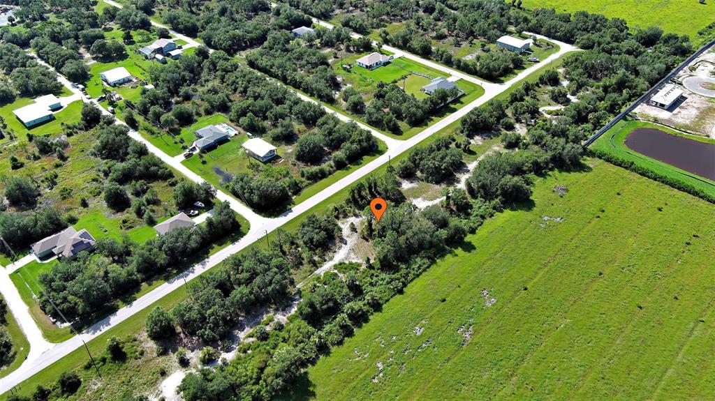 An aerial view shows a vacant, tree-covered lot marked with a pin in a rural neighborhood — 13441 GREEN GULF BOULEVARD, PUNTA GORDA, FL