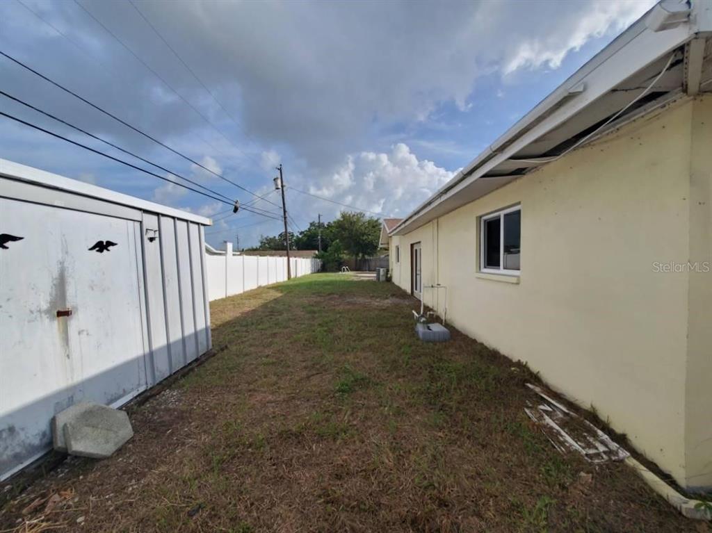 A backyard features a concrete patio, an empty swimming pool, and a wooden privacy fence — 9956 136TH STREET, SEMINOLE, FL