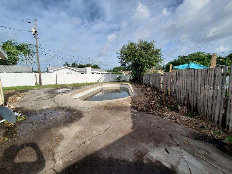 A side yard with a metal shed, a yellow house exterior, and a white fence — 9956 136TH STREET, SEMINOLE, FL