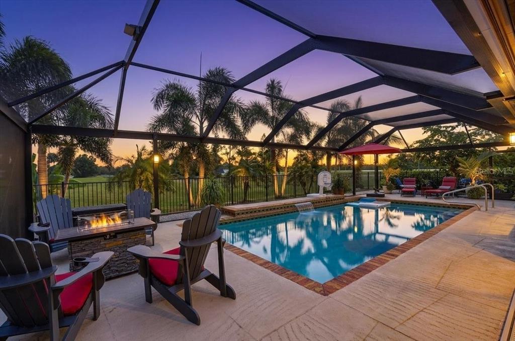 A screened-in pool patio features a fire pit, lounge chairs, and a view of trees — 24496 PEPPERCORN ROAD, PUNTA GORDA, FL