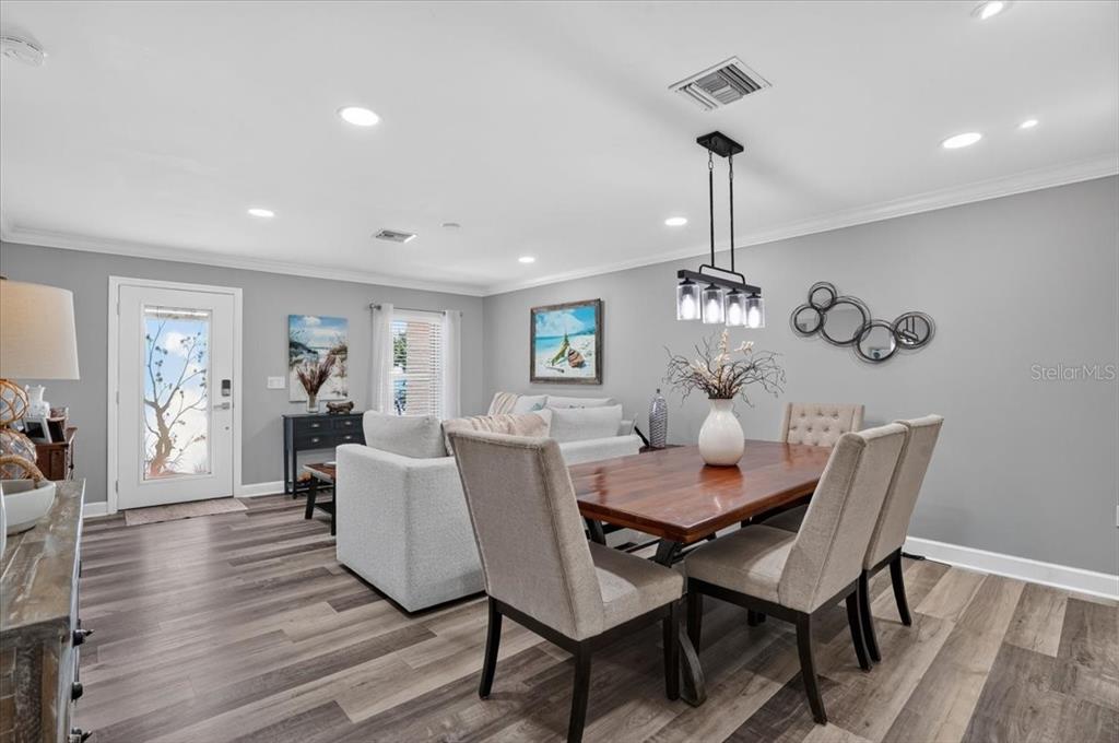 A dining area and living room with gray walls, wood-look flooring, and a wooden table — 24496 PEPPERCORN ROAD, PUNTA GORDA, FL