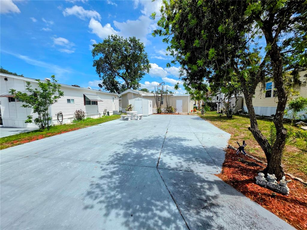 A paved driveway leads toward a white mobile home with a small storage shed — 7336 INTERNATIONAL CIRCLE, LAKE WALES, FL