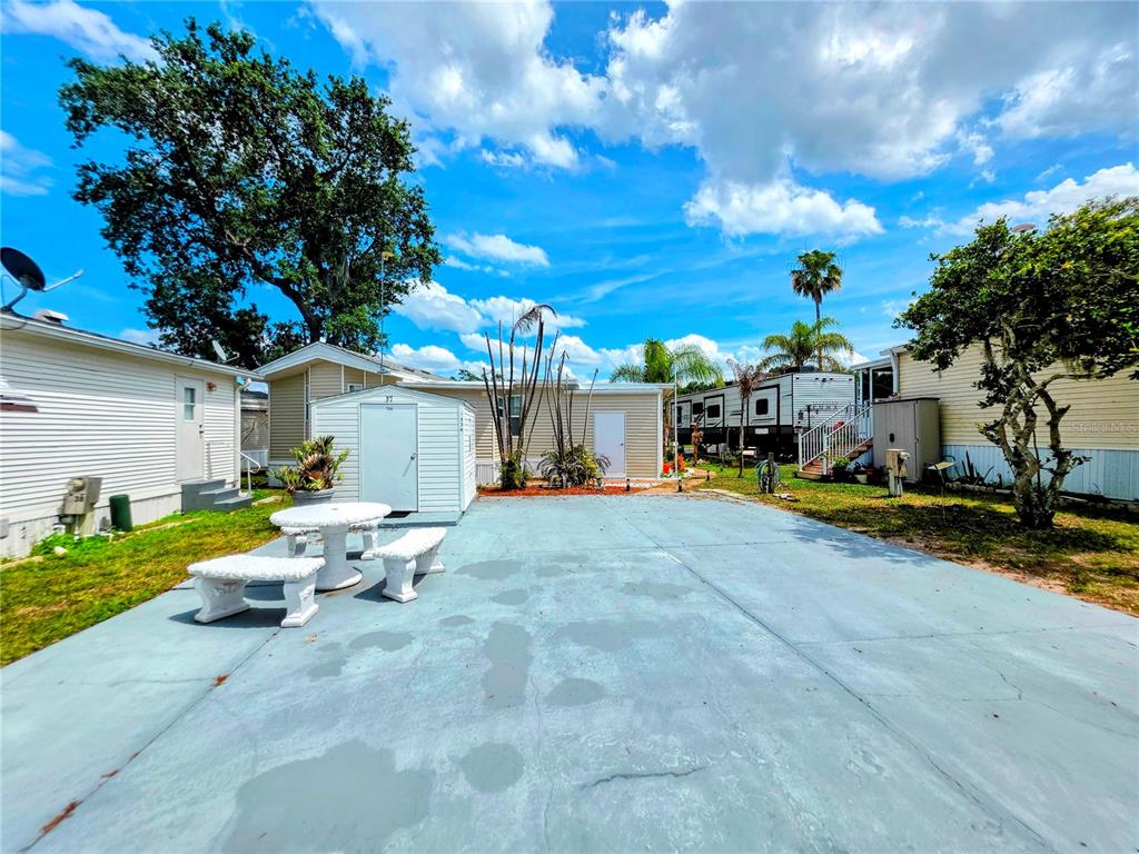 A concrete patio area features a white table and benches in front of a shed — 7336 INTERNATIONAL CIRCLE, LAKE WALES, FL
