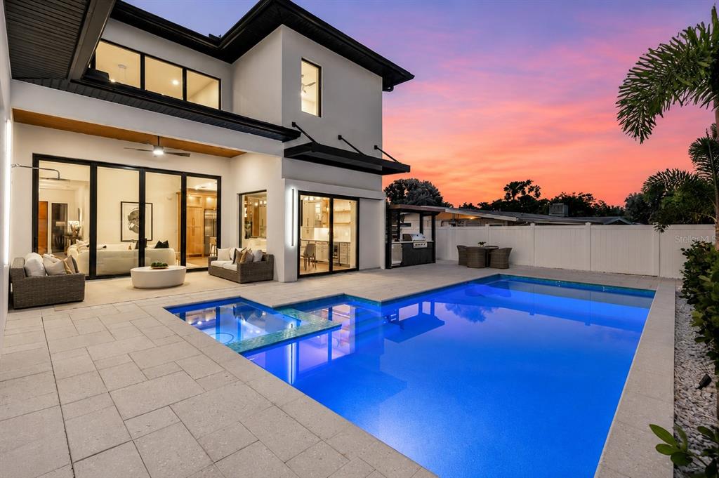 A modern two-story house exterior features a swimming pool, patio furniture, and a sunset sky — 2121 CLEMATIS COURT, SARASOTA, FL
