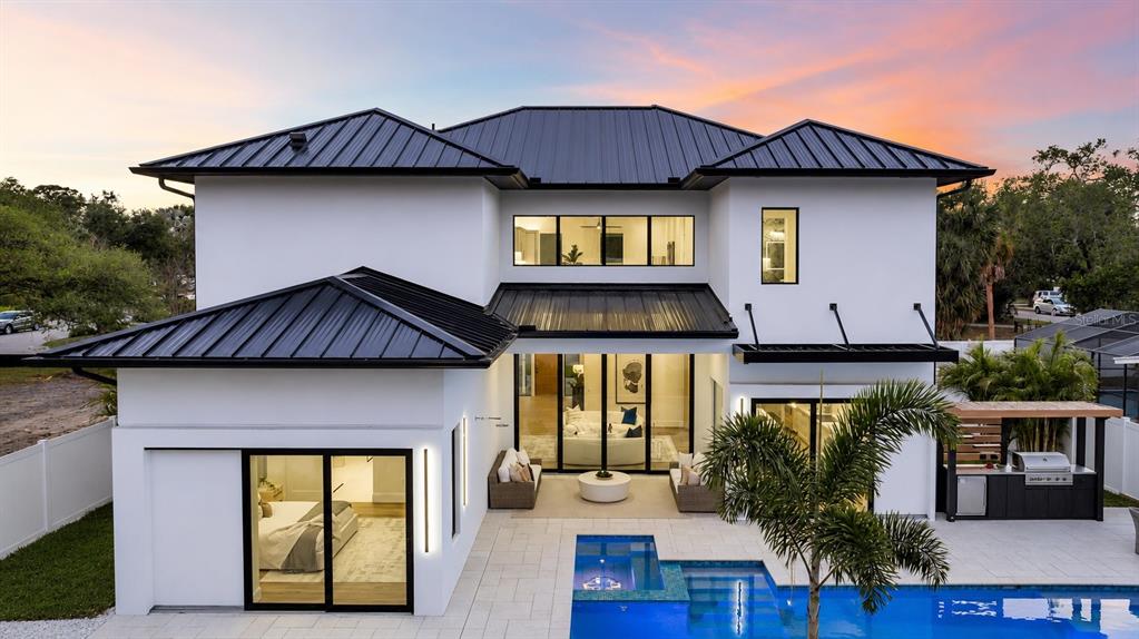 A modern two-story house with a black metal roof, white exterior, and a backyard pool — 2121 CLEMATIS COURT, SARASOTA, FL