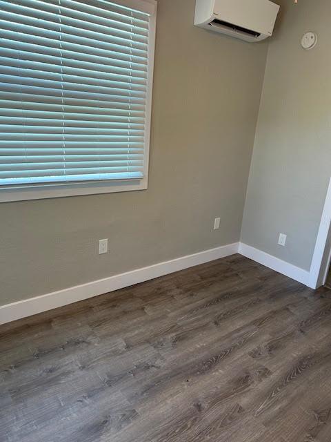 A room with grey walls, wood-look flooring, white trim, a window with blinds, and a wall-mounted AC unit — 514 S K Street, FL 33460, FL