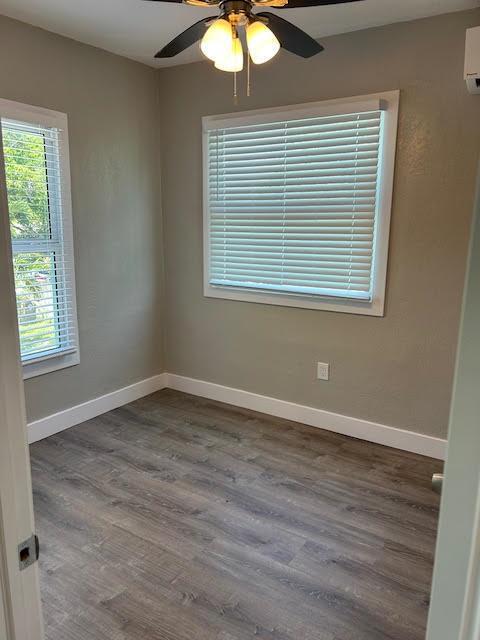 An empty room with light gray walls, wood-look flooring, two windows with blinds, and a fan — 514 S K Street, FL 33460, FL