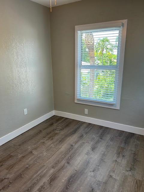 An empty room features gray walls, wood-look flooring, white trim, and a window with blinds — 514 S K Street, FL 33460, FL