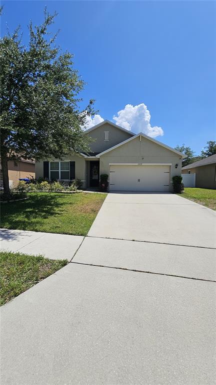 A single-story suburban house features a two-car garage, a concrete driveway, and a front lawn — 2459 VALHALLA DRIVE, TAVARES, FL