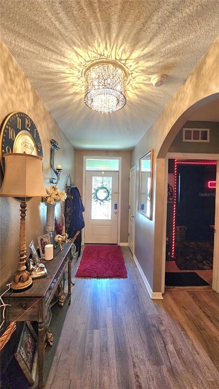 A hallway features wood-look flooring, a decorative ceiling light, a console table, and a front door — 2459 VALHALLA DRIVE, TAVARES, FL