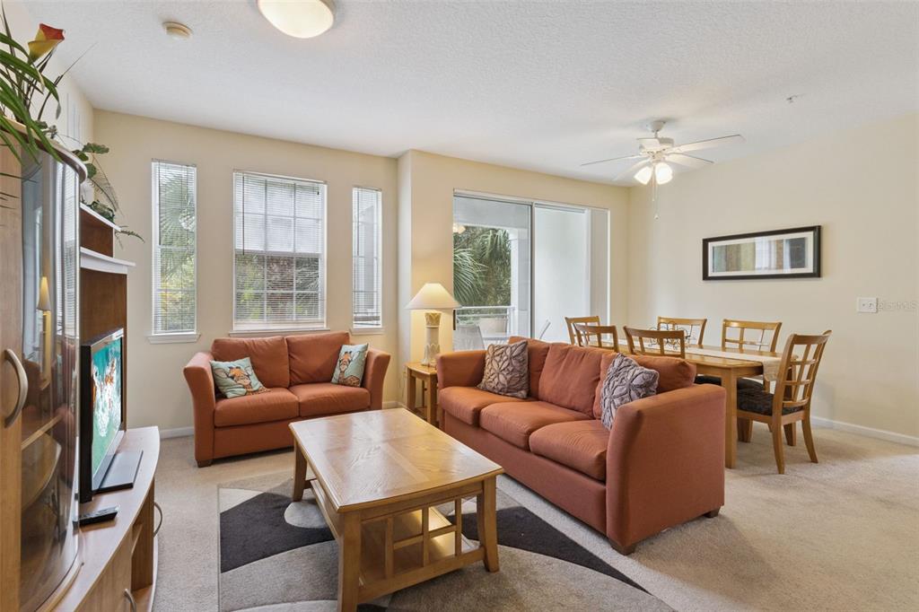 A living and dining room area features orange sofas, a wooden coffee table, and carpet — 5252 CANE ISLAND LOOP UNIT 204, KISSIMMEE, FL