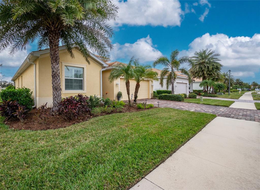 A single-story yellow house with a paved driveway, palm trees, and a green lawn — 6139 GRAND CYPRESS BOULEVARD, NORTH PORT, FL