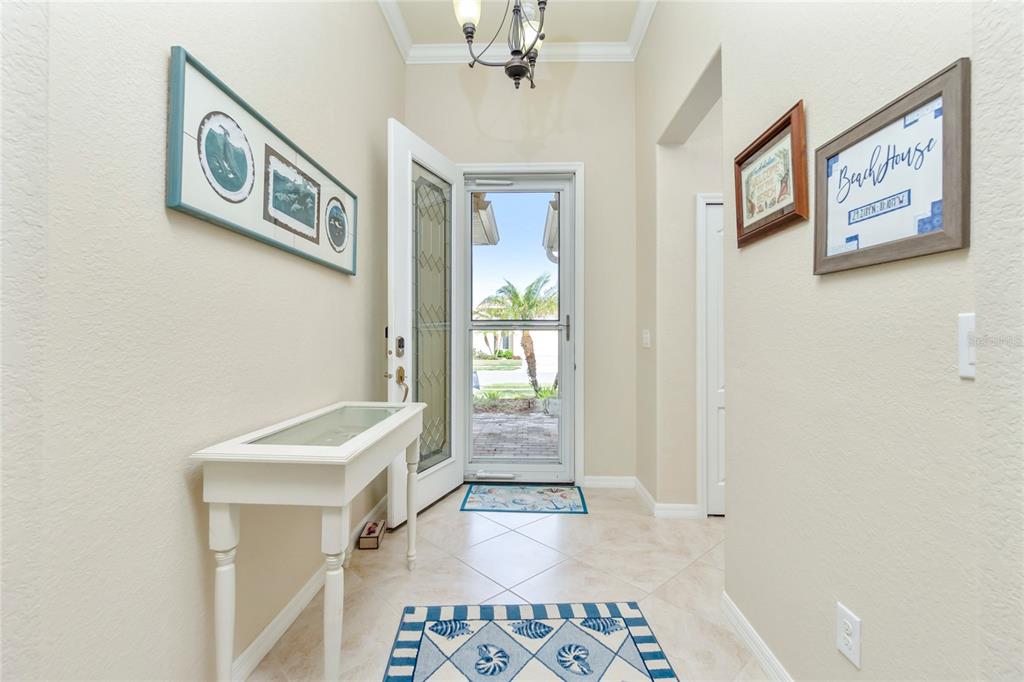 An entryway features a white console table, tile flooring, and a glass-paneled front door — 6139 GRAND CYPRESS BOULEVARD, NORTH PORT, FL